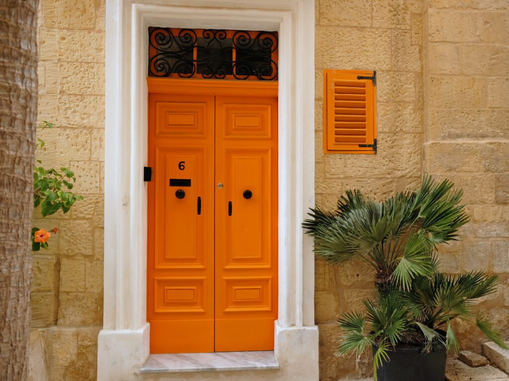 Bright orange casement doors add energy and charm to a warm, welcoming entryway.